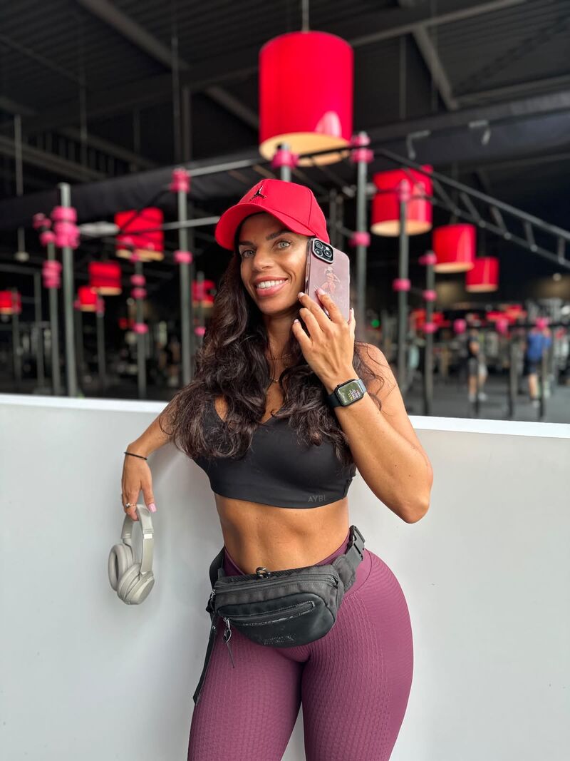 Esmeralda belt lachend met haar telefoon in de sportschool